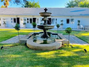 a fountain in the grass in front of a building at VIilla Vredenrust Guesthouse in Bloemfontein