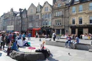 a group of people sitting around a fountain in a city at Grassmarket-Old Town Apartment in Edinburgh