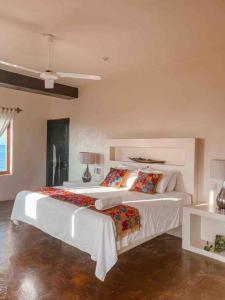 una camera da letto con un grande letto bianco con cuscini di Casa Conti Agua Blanca a Playa Agua Blanca