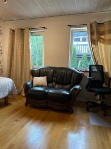 un sofá de cuero en una sala de estar con ventana en Stockholm-Arlanda privat rum i rymlig villa gratis wifi 1Gb fiber parkering Room1 en Täby