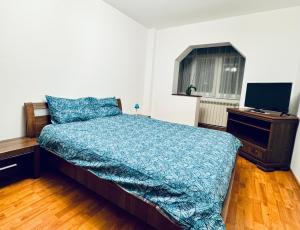 a bedroom with a bed with a blue comforter and a television at Altheda Living Eroilor 116-A4 in Suceava