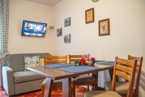 Un comedor con mesa y sillas y un televisor. en Maison Ostaria MyHolidayLivigno, en Livigno