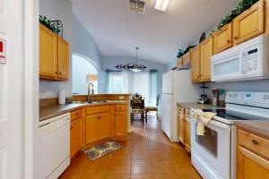 a kitchen with wooden cabinets and white appliances at Paradise Villa in Davenport