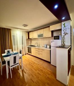 a kitchen with a table and a white refrigerator at Altheda Living Eroilor 116-A4 in Suceava
