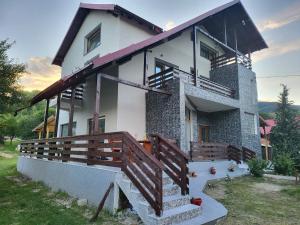 a house with a balcony and a wooden fence at Pensiunea Ricky in Căpăţîneni-Ungureni