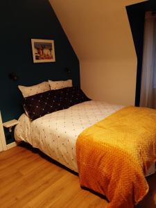 um quarto com uma cama com um cobertor amarelo em Le Refuge du Hibou em Beaurains