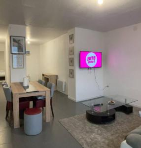 a living room with a table and a tv on the wall at Maison entière proche circuit des 24 heures in Le Mans