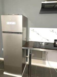 a kitchen with a stainless steel refrigerator and a table at Maison entière proche circuit des 24 heures in Le Mans