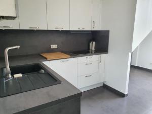 eine Küche mit weißen Schränken und einem Waschbecken in der Unterkunft Appartement F3 de 60M² à 20 minutes de Paris. in Yerres