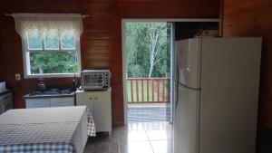a kitchen with a refrigerator and an open door at Refúgio das Uvas * Casa do Lago in Frederico Westphalen