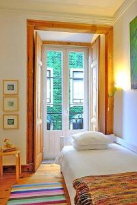 1 dormitorio con cama y ventana grande en PEN-ARTS apartment- PRINCIPE REAL garden - BAIRRO ALTO, en Lisboa