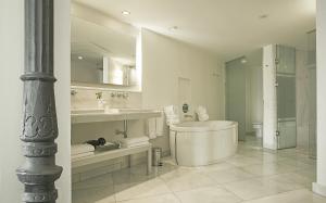 a white bathroom with a tub and a sink at Hospes Puerta de Alcalá, a Member of Design Hotels in Madrid
