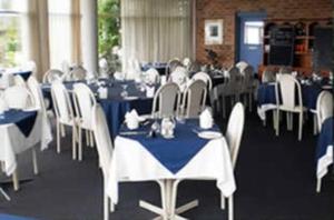 una stanza con tavoli e sedie con tovaglie blu e bianche di Lake Haven Motor Inn a Gorokan