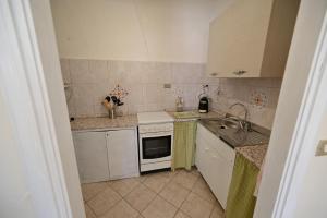 una pequeña cocina con armarios blancos y fregadero en CASA LETIZIA, en Ozzano Monferrato