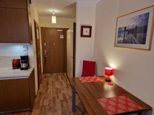 a small kitchen with a wooden table and a red chair at Apartament TRZY POMOSTY Villa Mistral in Świnoujście +36 photos