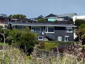 une grande maison avec une clôture devant elle dans l'établissement Churchill Oasis by the sea, à Tauranga