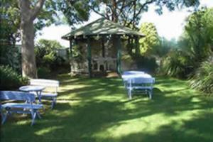 a gazebo with tables and benches in a yard at Lake Haven Motor Inn in Gorokan