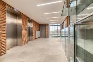 un corridoio dell'ufficio con una parete di mattoni e porte in vetro di Apartament Figo a Stettino