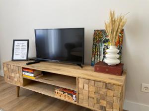 a flat screen tv sitting on top of a wooden entertainment center at ByAndreea Apartaments EtxeBat in Guernica y Luno