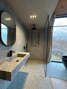 ein Badezimmer mit einem großen Spiegel und einem Waschbecken in der Unterkunft North Alpine Villas in Bogë