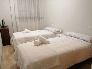 two beds in a hotel room with towels on them at Apartamento La Muralla II in Baena