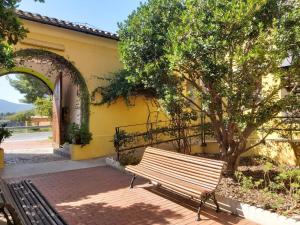 a bench sitting next to a yellow building with a tree at El Castellet Fanzara in Fanzara