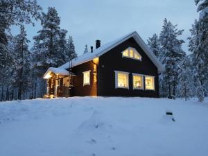 a house in the snow with lights on at Villa Havu holiday home in Pyhä/Lapland in Pyhätunturi