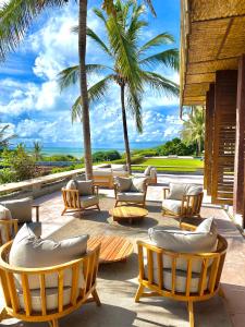 a patio with a bunch of chairs and palm trees at Casa da Gameleira in Baía Formosa