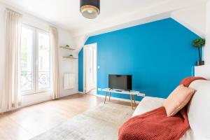 Elle comprend un salon doté d'un mur bleu et d'une télévision. dans l'établissement Nets Inn Apartments - La Villette, à Paris