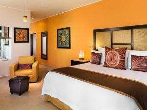 um quarto de hotel com uma cama grande e uma cadeira em El Dorado Maroma Catamarán, Cenote & More Inclusive em Playa del Carmen