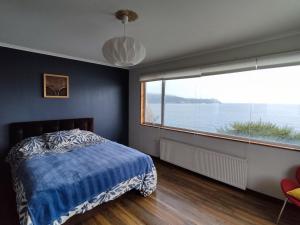 a bedroom with a bed and a large window at BuenaVida Hostel, Habitación amplia con baño en suite y vista al mar in Niebla