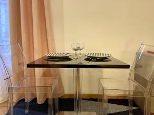 - une table en verre avec 2 assiettes et des verres à vin dans l'établissement Appartement le Paul Bert Auxerre Les Quais 2 personnes, à Auxerre