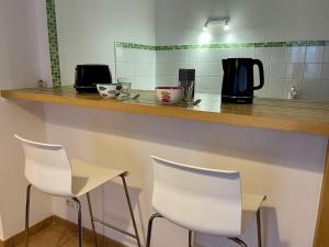 a bar with two white chairs and a counter at Appartement le Paul Bert Auxerre Les Quais 2 personnes in Auxerre