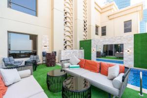 patio con sofá, sillas y piscina en ELAN RIMAL SADAF Suites, en Dubái