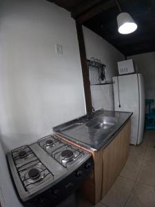 uma cozinha com um fogão e um lavatório em Morada da Xica em Guarda do Embaú