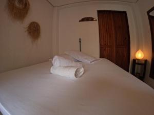 uma cama branca com toalhas num quarto em Morada da Xica em Guarda do Embaú