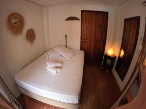 um quarto com uma cama branca e toalhas em Morada da Xica em Guarda do Embaú