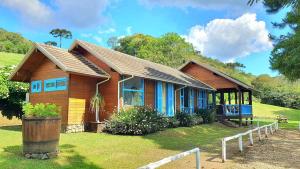a small wooden house on a grass field at Rancho das Neves - Rancho Queimado - SC in Rancho Queimado
