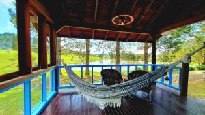 a hammock on a porch with a view of a lake at Rancho das Neves - Rancho Queimado - SC in Rancho Queimado