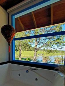 a bathroom window with a view of a tree at Rancho das Neves - Rancho Queimado - SC in Rancho Queimado