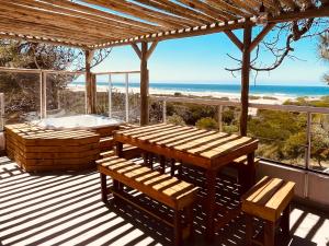 a deck with a hot tub and a table and benches at Jaina Resort & Spa in Mar de las Pampas