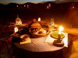 a table with a candle and a bowl of food at Caravane de Reve in Mhamid