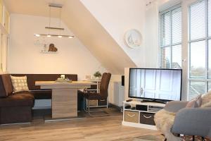 - un salon avec une télévision, un canapé et une table dans l'établissement Apartmentvermittlung Mehr als Meer - Objekt 15, à Niendorf