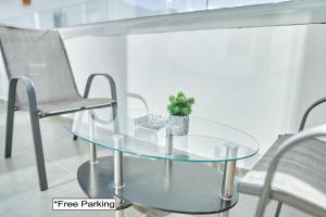 uma mesa de vidro com uma planta em vaso ao lado de duas cadeiras em Nissi Avenue Suites em Agia Napa