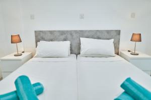 a bedroom with two white beds and two lamps at Nissi Avenue Suites in Ayia Napa