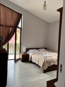 a bedroom with a bed and a large window at Guest House PIROSMANI in Tsqnetʼi