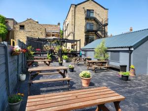 a patio with wooden picnic tables and plants at The Royal Oak Hotel in Highpeak Junction