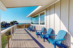 Eine Reihe blauer Stühle auf einer Veranda in der Unterkunft Panoramic Ocean View Home in Elk with Beach Access in Elk