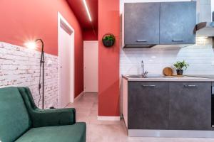 uma cozinha com paredes vermelhas e um sofá verde em Tartini Lofts em Bolonha