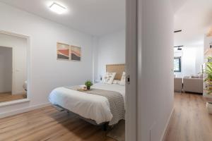 a white bedroom with a bed and a living room at Apartamento Casiopea in Santander